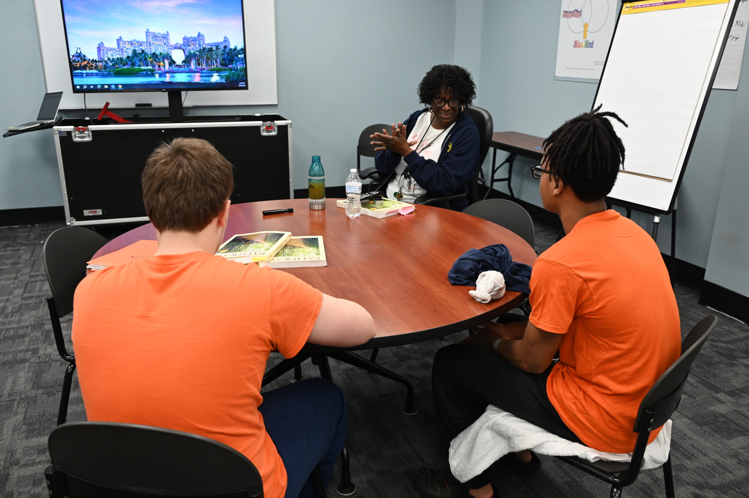 a counselor and two youth speaking while seated at a round table