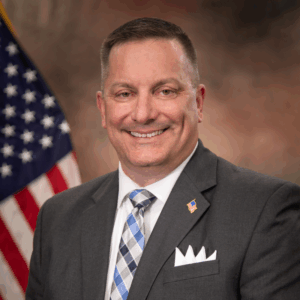 headshot photo of Patrick Mirandy with American flag in background