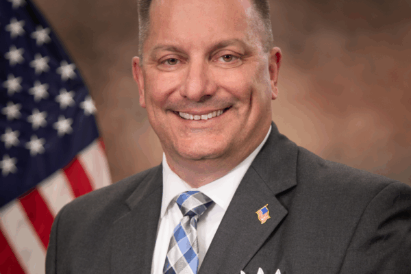 headshot photo of Patrick Mirandy with American flag in background