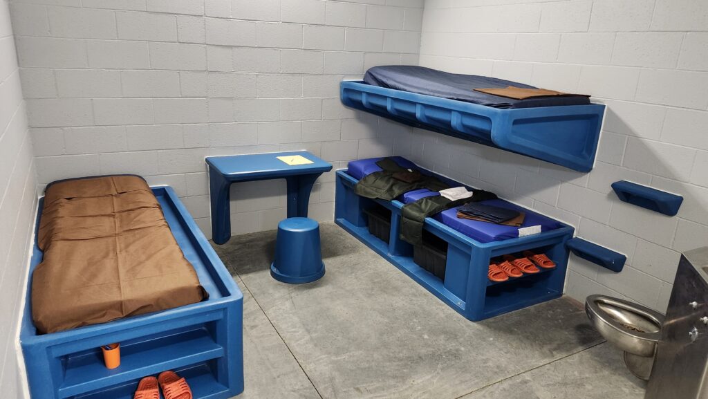 blue plastic bunk beds in a jail cell