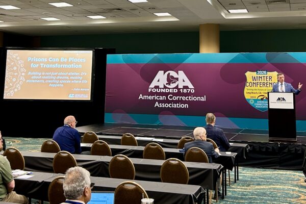 Ryan Thornell speaking at a conference on stage with ACA logo background