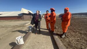 woman and three men in orange jumpsuits at prison garden