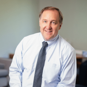 headshot photo of David Mahoney wearing shirt and tie in office setting