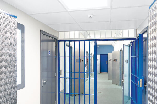 ceiling panels in a prison with blue bars and metal doors