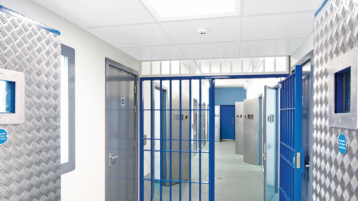 ceiling panels in a prison with blue bars and metal doors