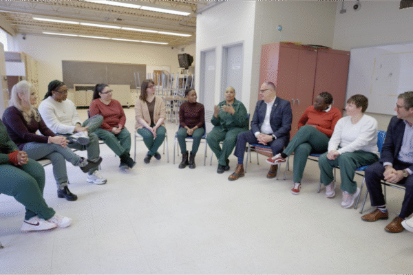NYSDOCCS Commissioner Dan Martuscello and Bedford Hills Correctional Facility staff seated in a semicircle in a prison classroom