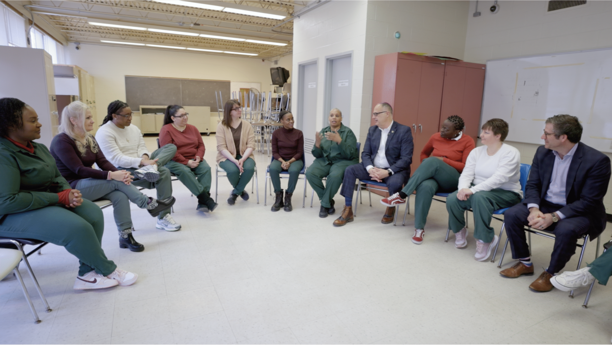 NYSDOCCS Commissioner Dan Martuscello and Bedford Hills Correctional Facility staff seated in a semicircle in a prison classroom