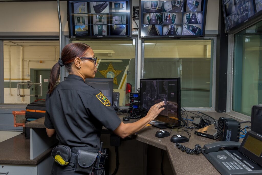 female sheriff's office employee working in control room of a correctional facility