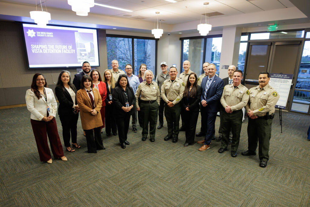 San Diego County Sheriff's Office representatives pose in conference room with video screen in background