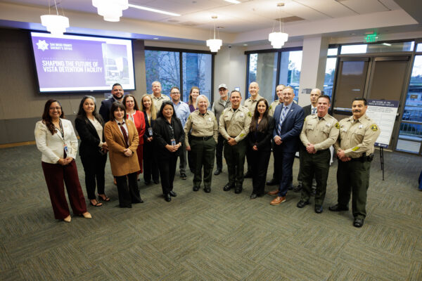 San Diego County Sheriff's Office representatives pose in conference room with video screen in background
