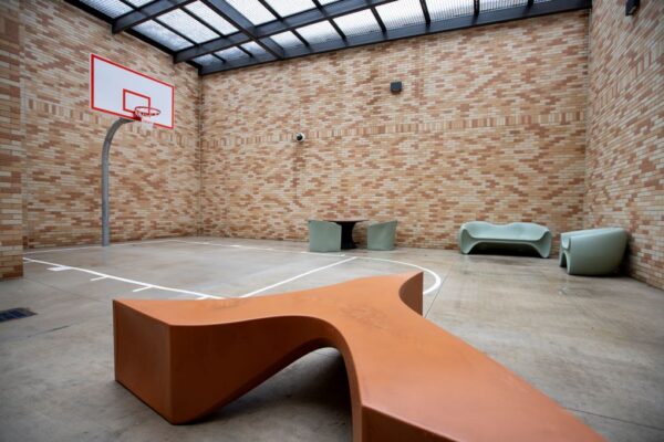 recreation area with basketball court and red bench and brick wall