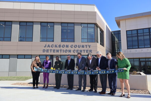 men and women at a ribbon cutting ceremony outside new Jackson Couty Detention Center in Missouri