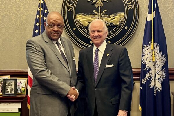 Dennis R. Patterson Sr. shaking hands with Gov. Henry McMaster is front of South Carolina state seal