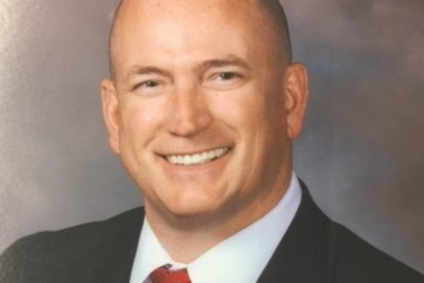 headshot photo of Eric Aldridge wearing black suit and red tie