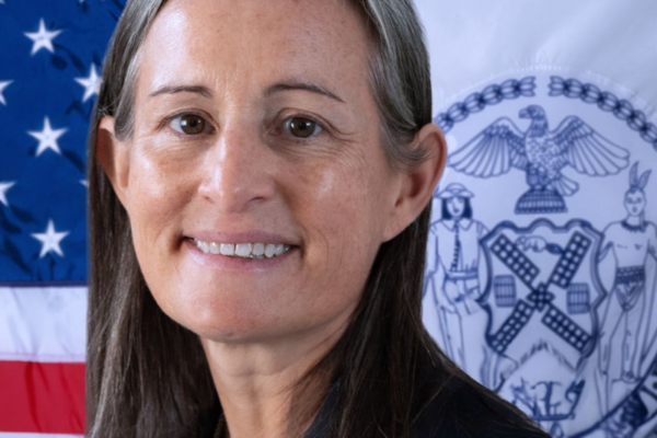 headshot photo of Margaret Egan with American and New York City flags in background