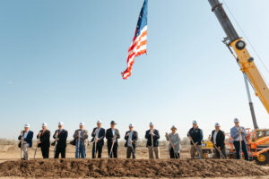 individuals at a groundbreaking ceremony at construction site with crane holding American flag