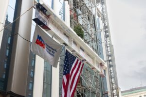 steel beam with NYC and American flags being placed at construction site