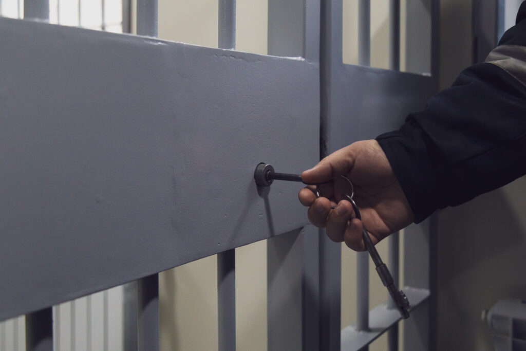 hand unlocking a jail cell door with key