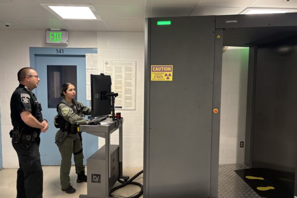 correctional officers using a body scanner
